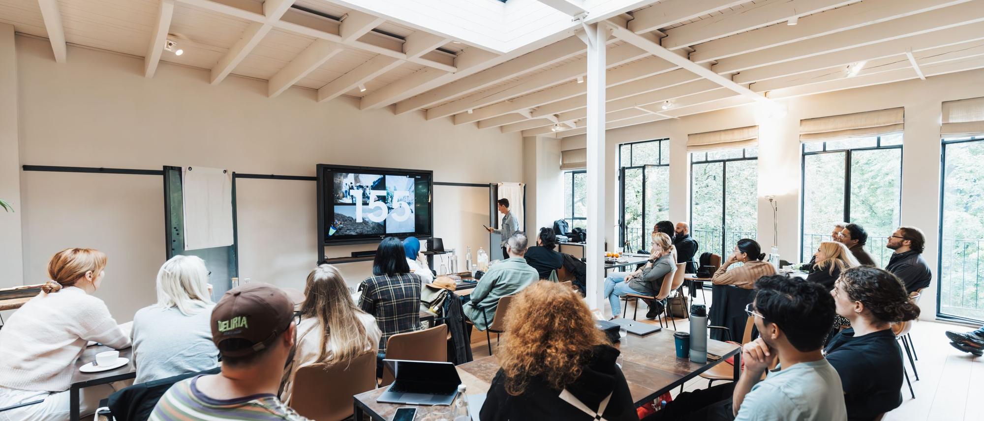 A group of adults at a hands-on workshop in a bright, skylit room with wooden beams